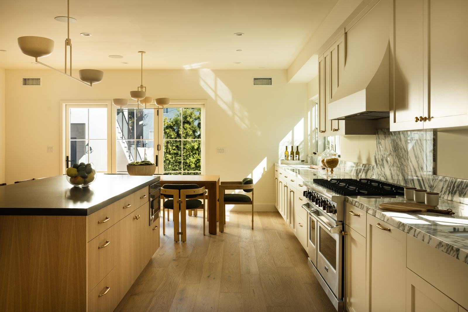 Wide kitchen shot with a black-and-oak island and marble backsplash