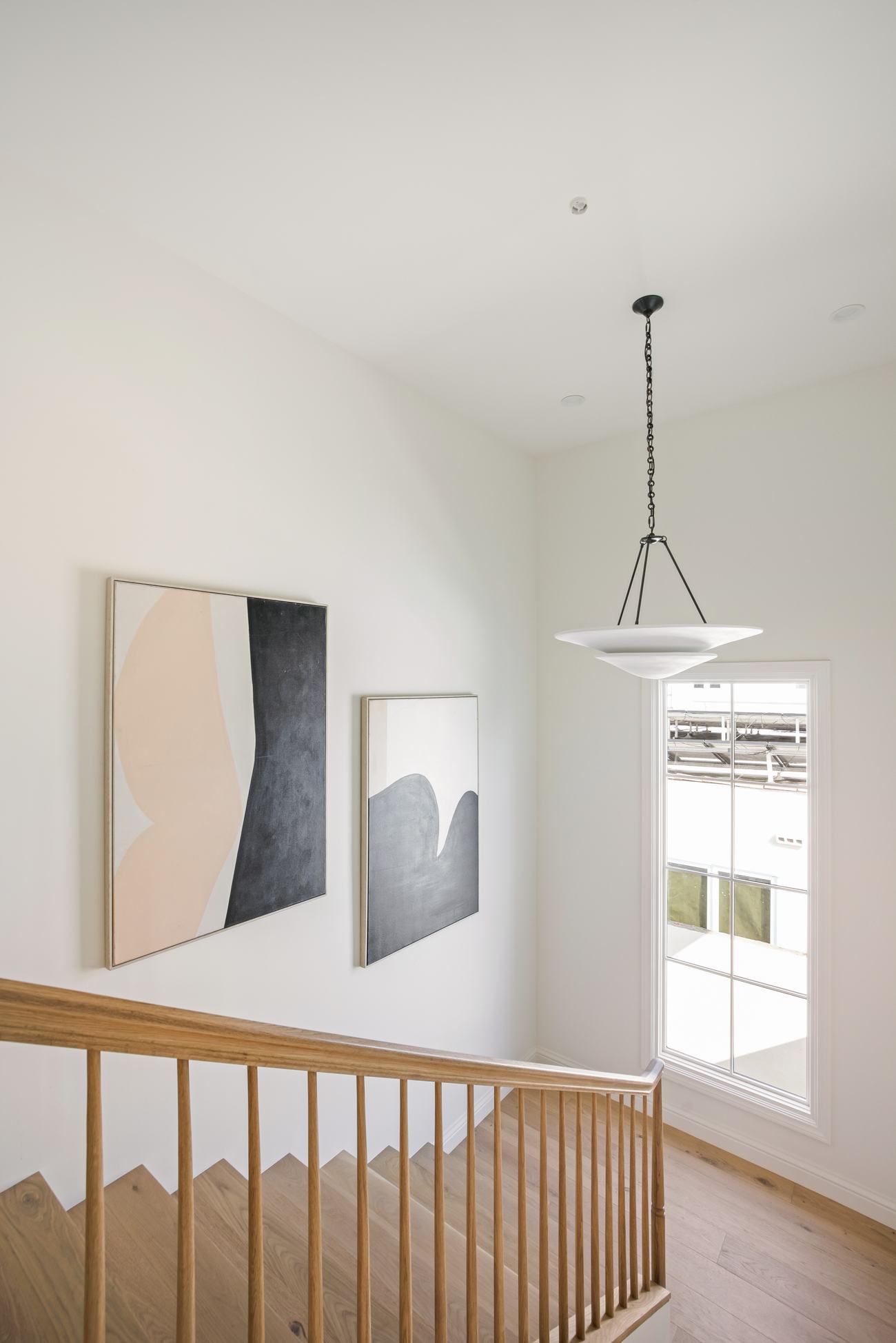 Stairwell landing with a pair of abstract paintings and an alabaster pendant